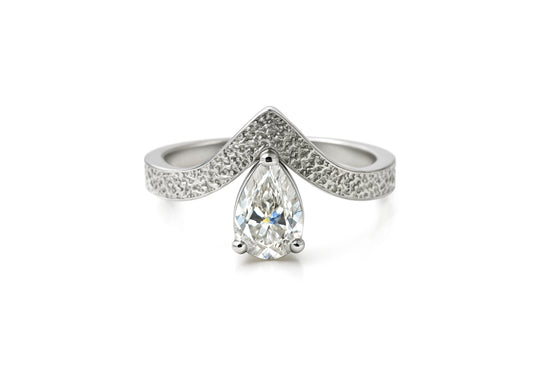 Textured V-shaped ring with pear-shaped moissanite.