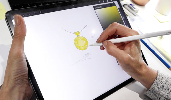 Croquis de bijou réalisé sur tablette numérique à l’aide d’un stylet, illustrant un pendentif rond en or jaune au cœur d’un processus de création sur mesure.