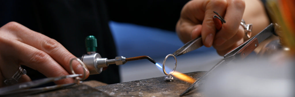 Soudure d'une bague à l’aide d’un chalumeau et d’une pince en atelier de joaillerie.
