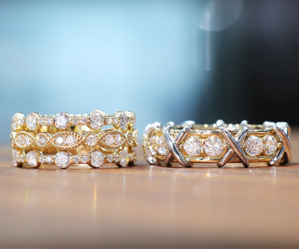 Ensemble de bagues créées sur mesure, l’une pour femme et l’autre pour homme. La bague femme est composée de trois anneaux empilés en or jaune, sertis de diamants ronds et marquises en serti clos et pavé, dans un design riche et étincelant. La bague homme, plus sobre mais audacieuse, présente une ligne de diamants sertis en rail, encadrés de croisés en or blanc formant un motif “X” sculptural sur le dessus du corps de bague.
