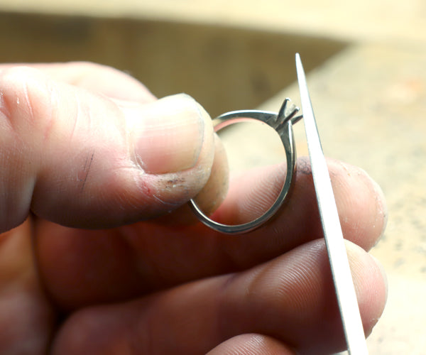 Joaillier limant une bague en or lors d'une réparation en atelier.