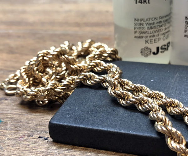 Chaîne en or posée sur une plaque de test avec flacons JSP pour l’analyse du carat.